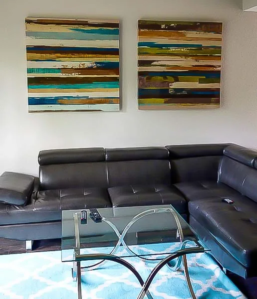 Cozy living area in Austin sober living home with sectional sofa, glass coffee table, and wall art.