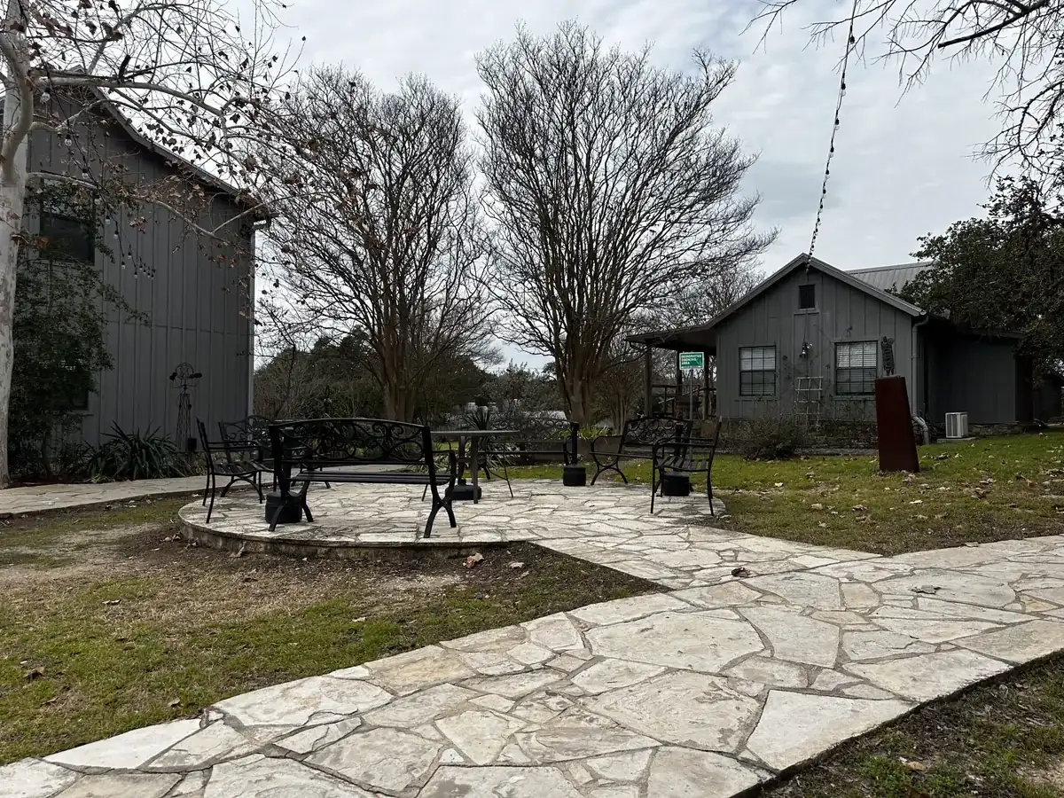 Stone patio under live oaks with wicker seating at Nova Recovery Center’s Texas Hill Country rehab campus.