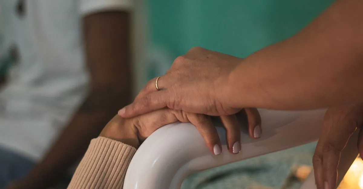 Close-up of comforting hands touching in a hospital room, symbolizing support and compassion.