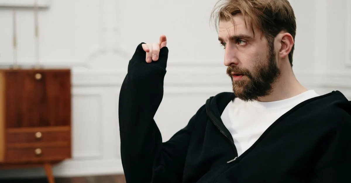 Thoughtful bearded man in a casual setting, indoors, engaging in conversation.