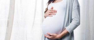 pregnant woman standing by a window