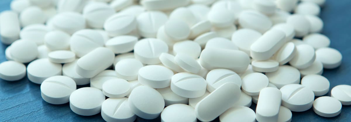 Close‑up of white Xanax-like tablets spilling across a surface, representing common misconceptions and misuse of alprazolam.