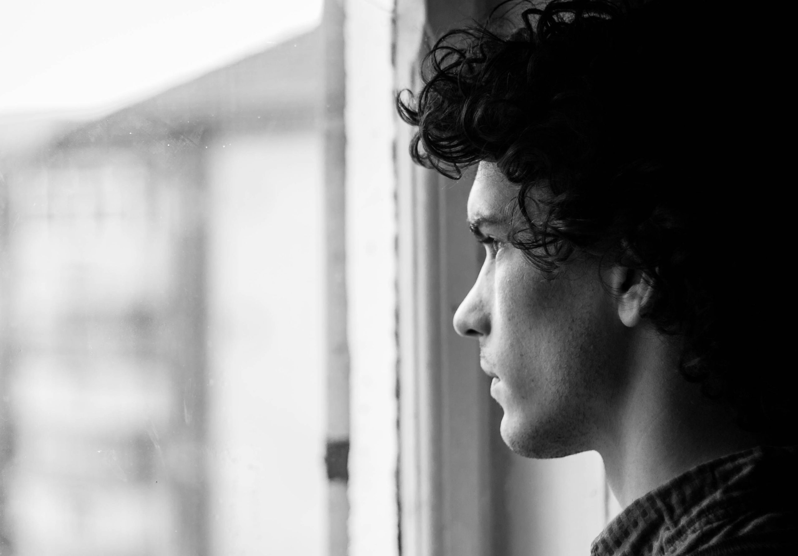 Young man gazes out a window.