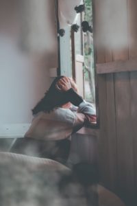 Woman suffering from withdrawal looking out a window.