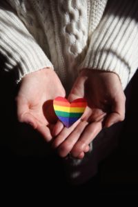 Woman holding a paper rainbow heart.
