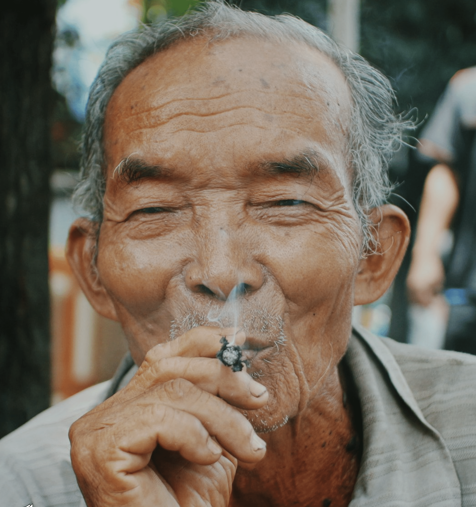 Elderly man with visible wrinkles smoking a hand-rolled substance, with smoke rising from his mouth, illustrating crack cocaine use.