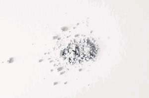 Pile of white powder resembling heroin on a white surface, symbolizing the dangers and addictive nature of opioid use.