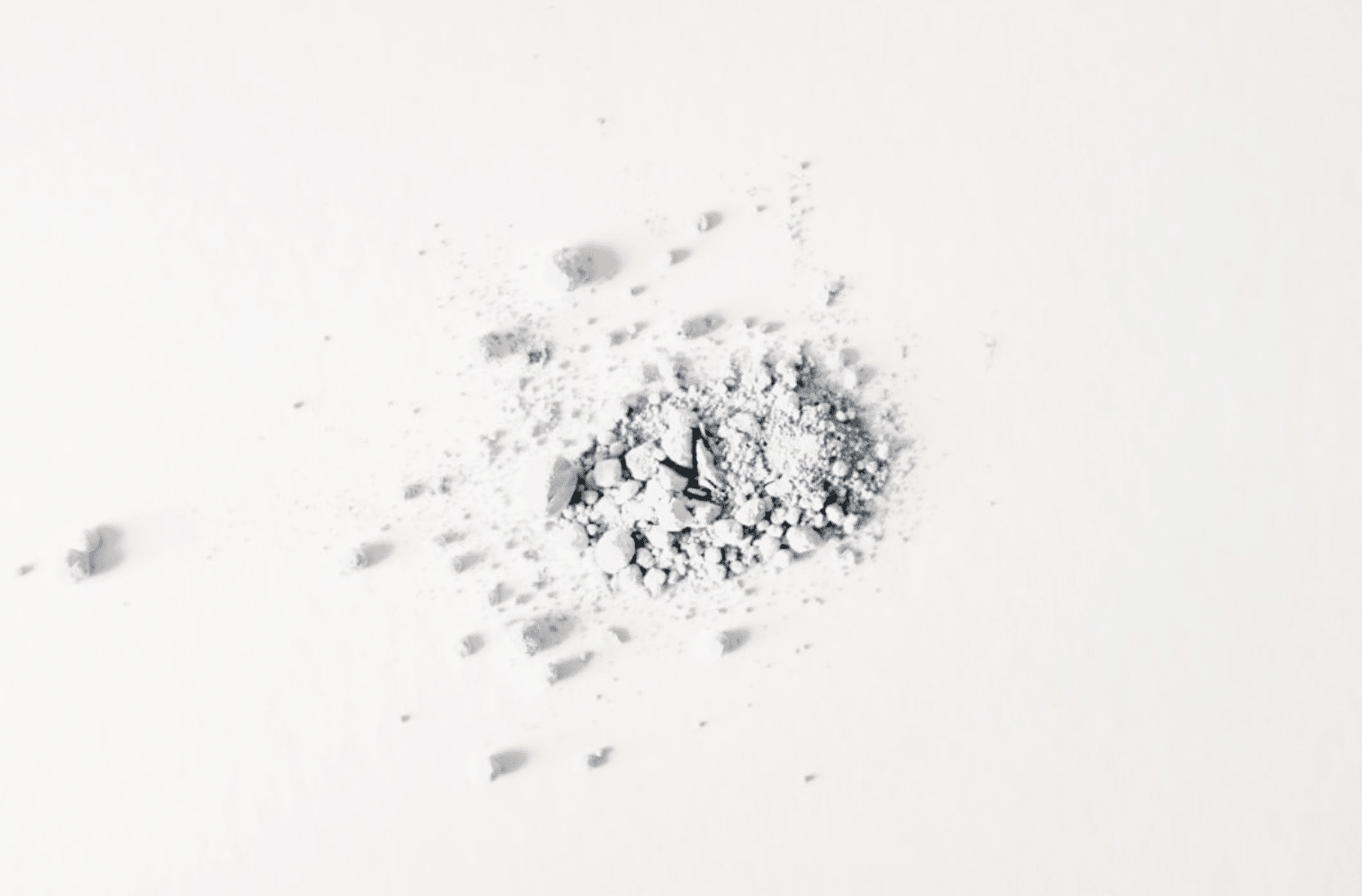 Pile of white powder resembling heroin on a white surface, symbolizing the dangers and addictive nature of opioid use.