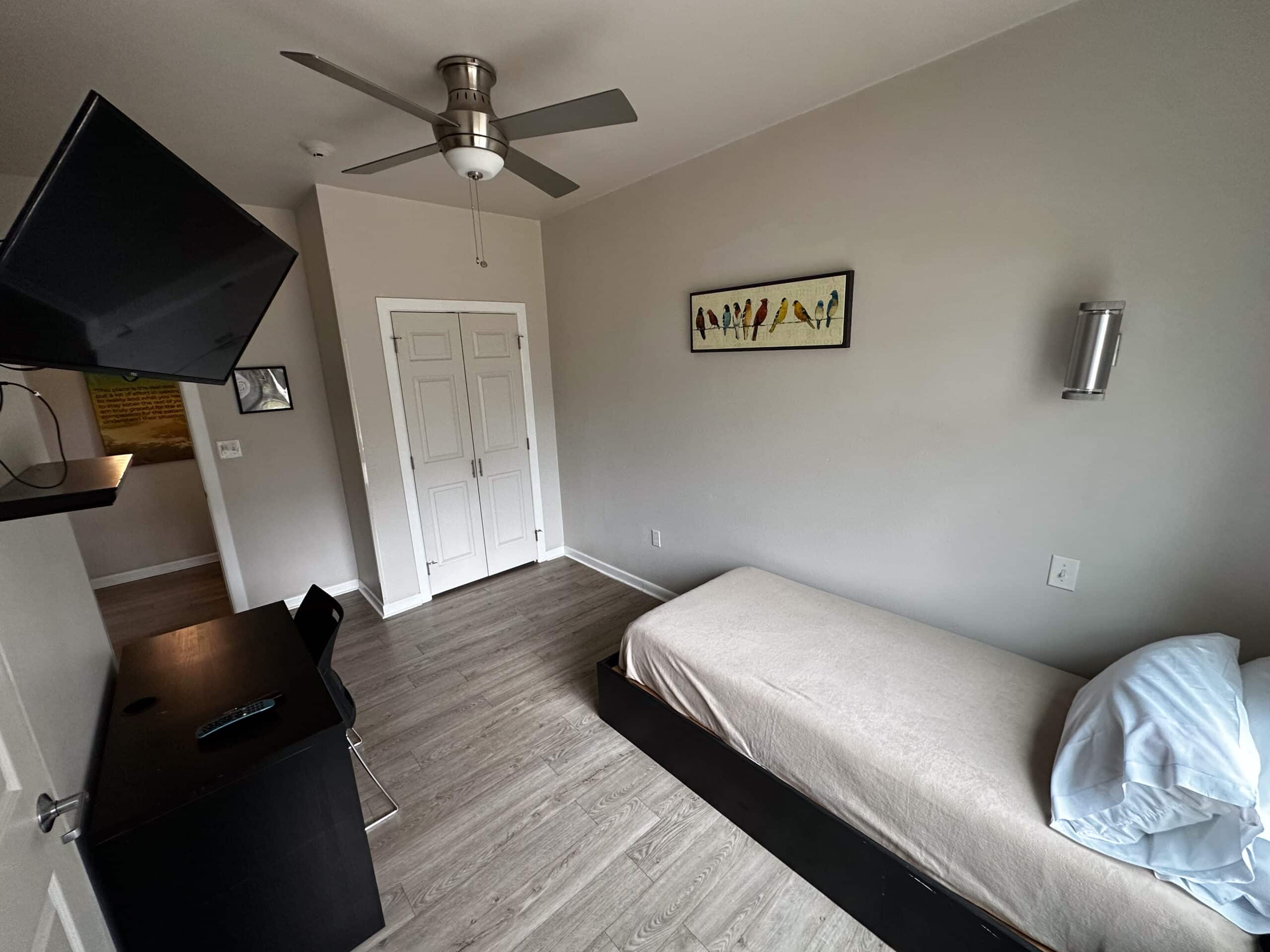 Single-bed private room at Briarwood Detox Center Austin with ceiling fan and bird artwork.