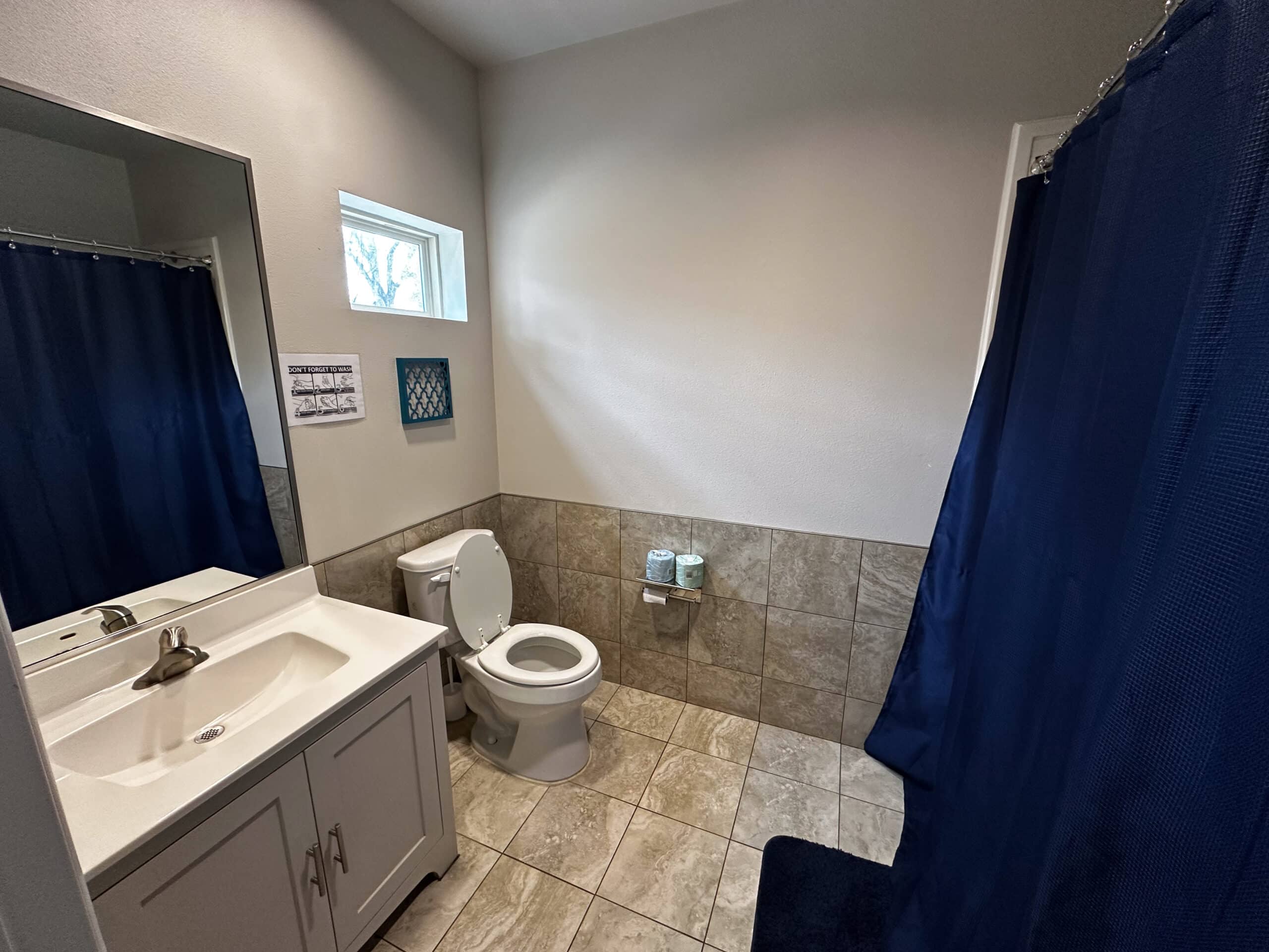 Bathroom interior at Briarwood Detox Center Austin with sink, toilet, and blue shower curtain.