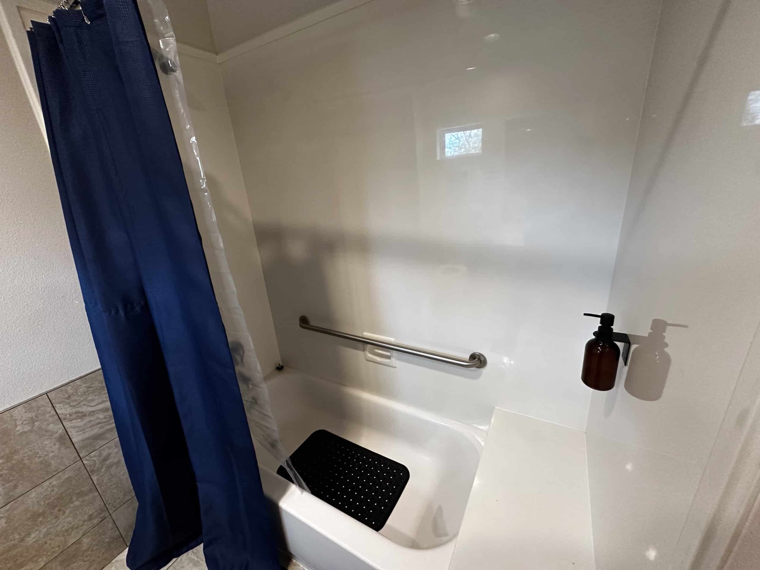 Accessible shower with safety rail and blue curtain at Briarwood Detox Center Austin.