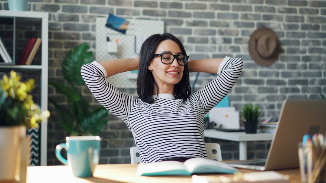 a woman sitting at a desk with her hands behind her head -- Photo by Vitaly Gariev on Unsplash