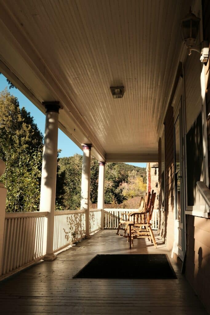 a porch with rocking chairs and a rug on it -- Photo by Julia Rodriguez on Unsplash