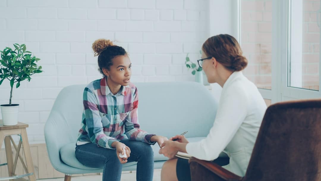 Therapist talking to a young woman on couch. -- Photo by Vitaly Gariev on Unsplash