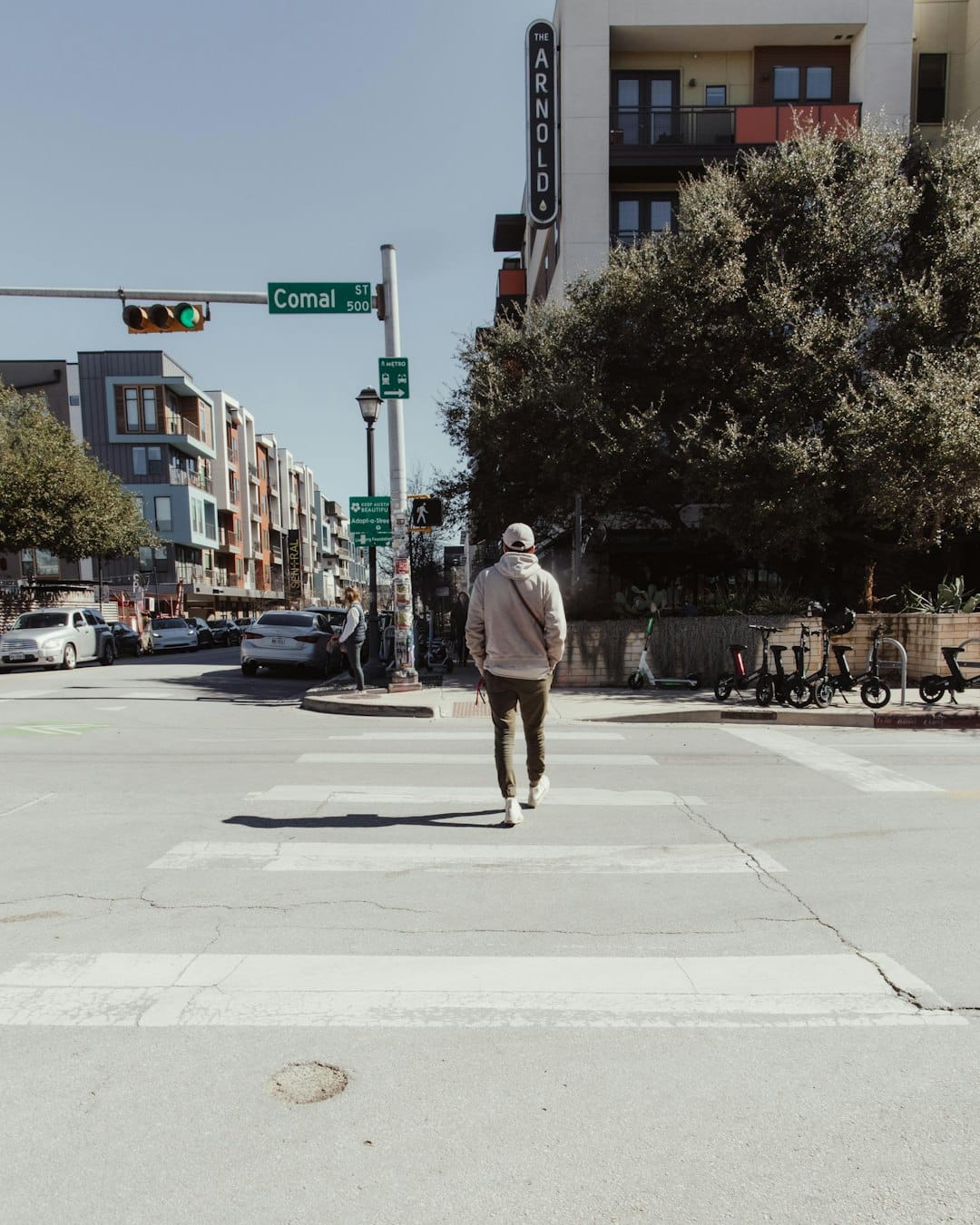 a man walking across a street next to a traffic light -- Photo by Tasha Jolley on Unsplash