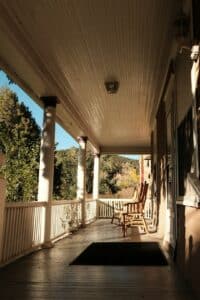a porch with rocking chairs and a rug on it -- Photo by Julia Rodriguez on Unsplash