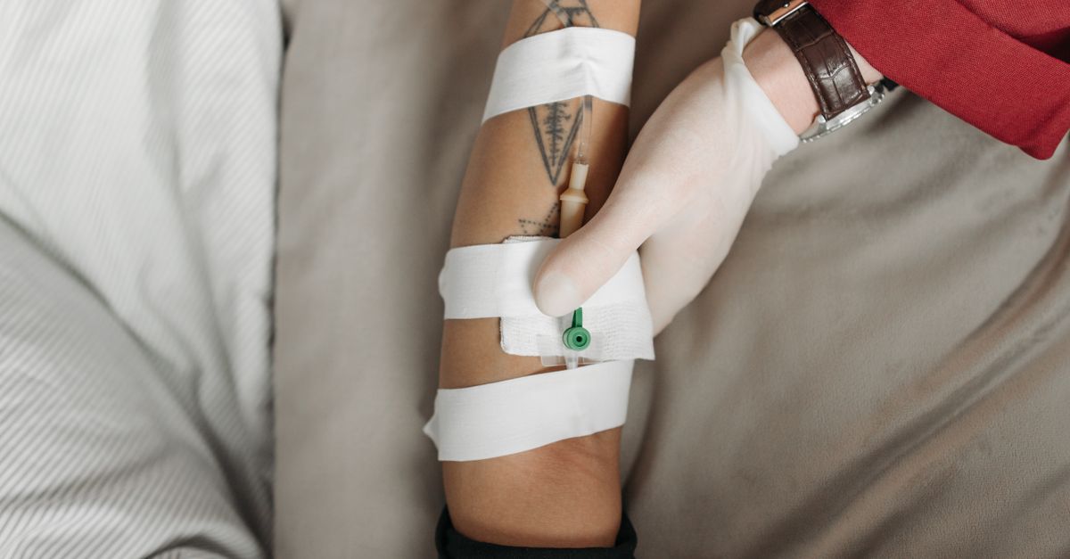 Close-up of a healthcare worker administering an IV to a patient's arm, focusing on the medical procedure.