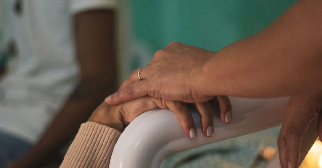 Close-up of comforting hands touching in a hospital room, symbolizing support and compassion.