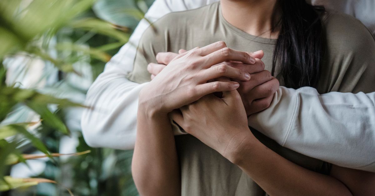 Tender embrace of a couple highlighting warmth and affection surrounded by greenery.