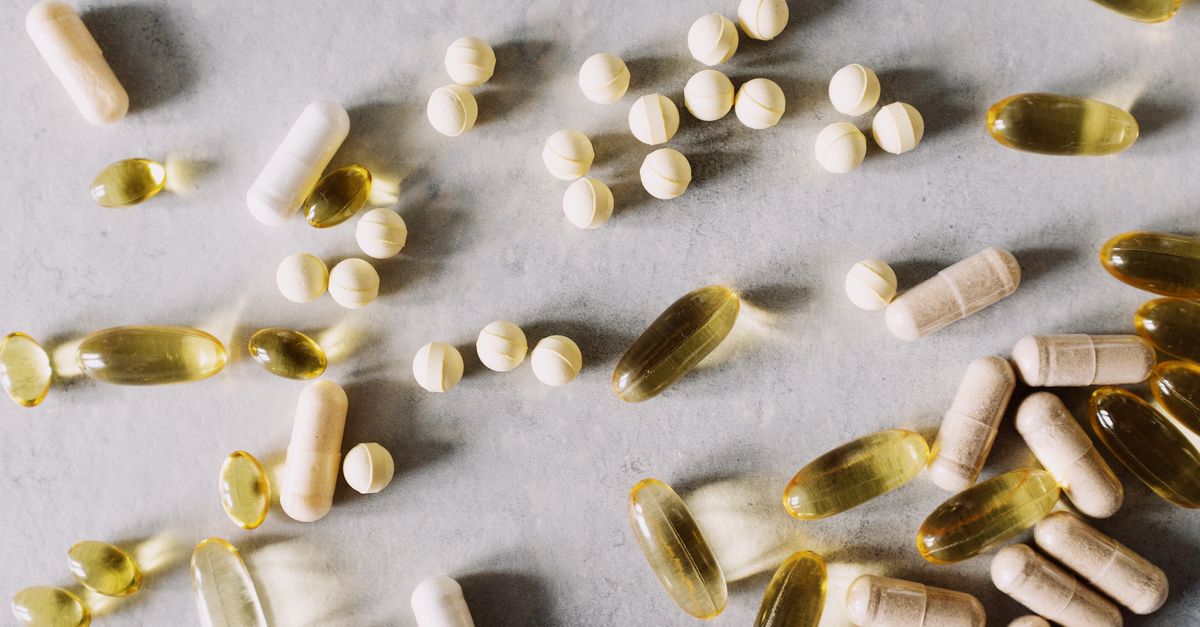 Top view of scattered set of pills and dietary supplements to prevent lack of vitamins on table in light studio