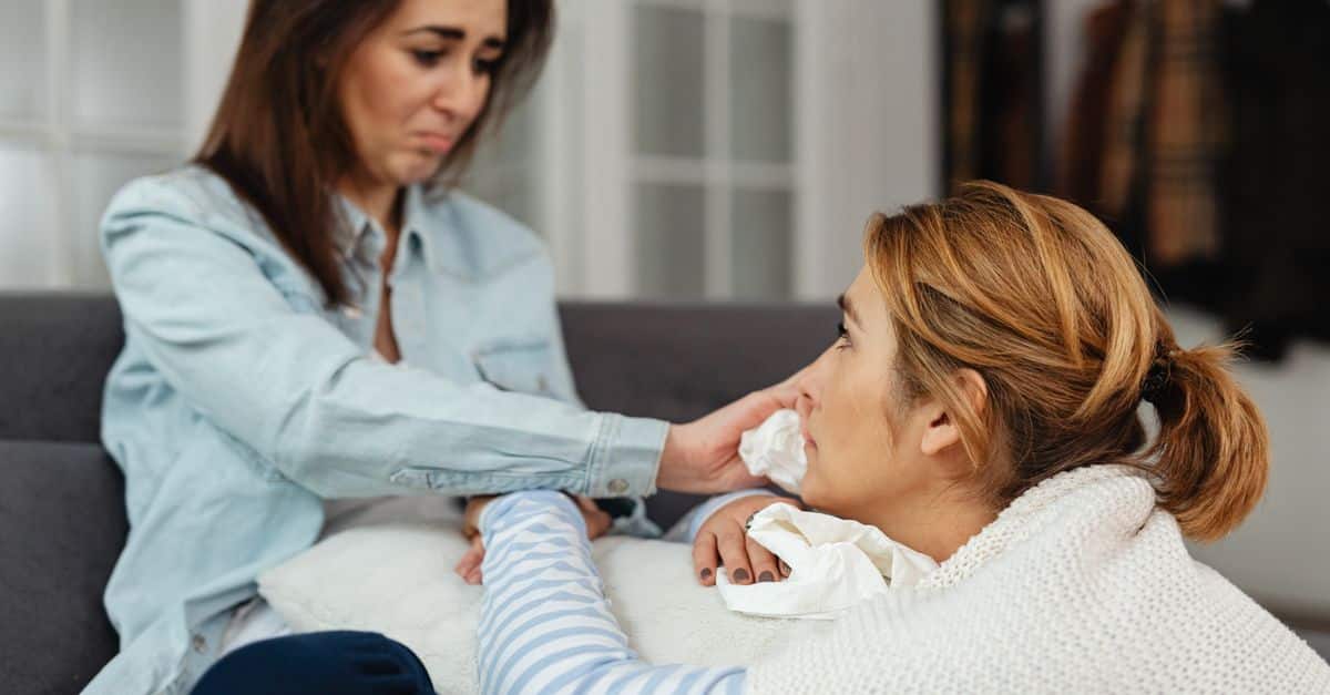 Two women share a moment of comfort and support indoors, expressing emotions.