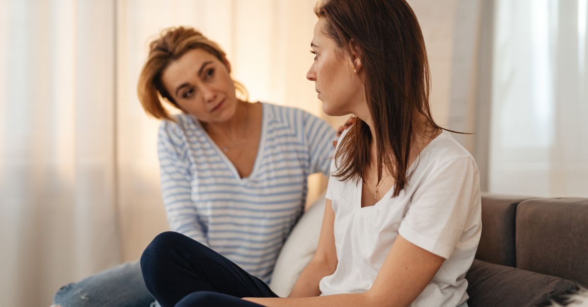 Two women having a heartfelt conversation on a couch, showing empathy and support.
